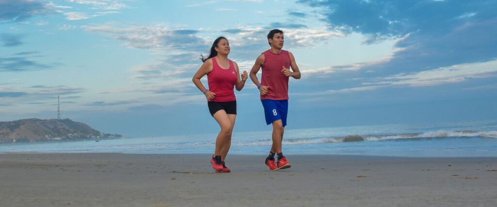 Active couple jogging on the beach, showing healthy legs — vein care at Saphena Vein Clinic